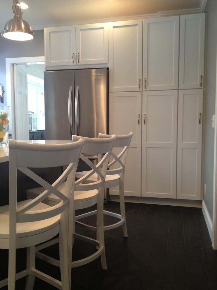 This is an example of a mid-sized contemporary separate kitchen in New York with recessed-panel cabinets, white cabinets, stainless steel appliances and with island.