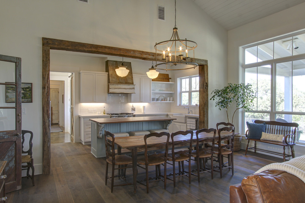 Inspiration for a large country open plan dining in Austin with white walls, dark hardwood floors, no fireplace and brown floor.