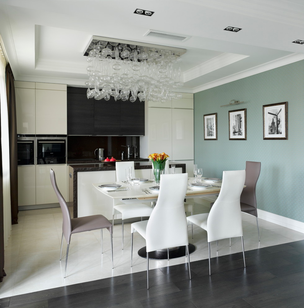 This is an example of a contemporary single-wall open plan kitchen in Moscow with flat-panel cabinets, granite benchtops, black splashback, black appliances, porcelain floors, with island and white cabinets.