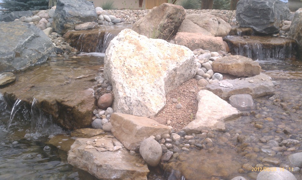 This is an example of a mid-sized rustic full sun backyard water fountain landscape in Denver.