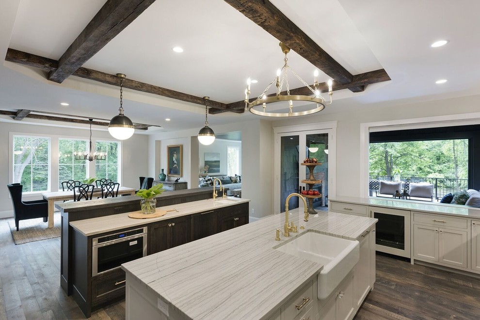 Large contemporary u-shaped open plan kitchen in Minneapolis with a farmhouse sink, recessed-panel cabinets, white cabinets, quartzite benchtops, blue splashback, subway tile splashback, stainless steel appliances, dark hardwood floors, multiple islands and brown floor.