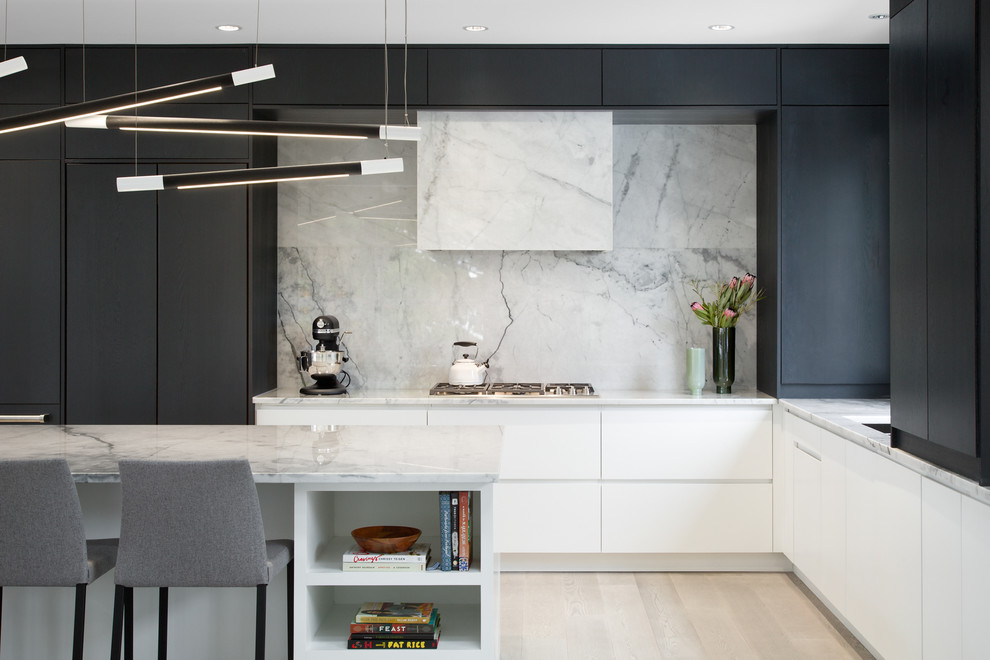 Large contemporary l-shaped open plan kitchen in Vancouver with an undermount sink, flat-panel cabinets, black cabinets, marble benchtops, white splashback, marble splashback, panelled appliances, with island, white benchtop, light hardwood floors and beige floor.