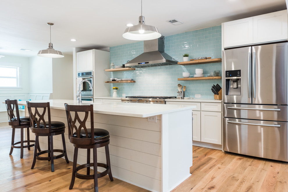 Inspiration for a large transitional galley light wood floor and beige floor open concept kitchen remodel in Charleston with an undermount sink, shaker cabinets, white cabinets, quartz countertops, blue backsplash, glass tile backsplash, stainless steel appliances and an island