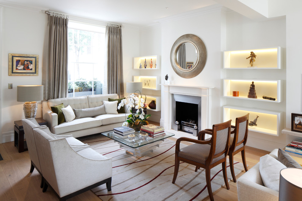 Design ideas for a transitional formal living room in London with white walls, light hardwood floors, a standard fireplace and a metal fireplace surround.