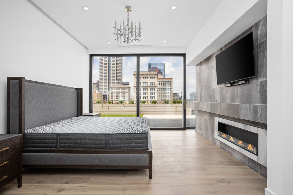 Mittelgroßes Modernes Hauptschlafzimmer mit weißer Wandfarbe, hellem Holzboden, Hängekamin, gefliester Kaminumrandung und buntem Boden in Indianapolis