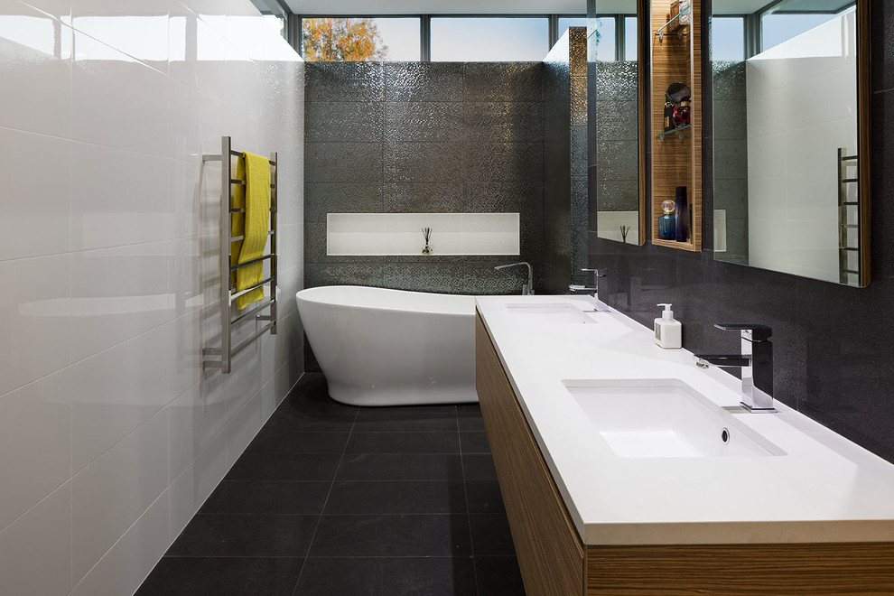 Inspiration for a large modern master bathroom in Perth with flat-panel cabinets, medium wood cabinets, a freestanding tub, an alcove shower, a one-piece toilet, multi-coloured tile, ceramic tile, beige walls, ceramic floors, an undermount sink, solid surface benchtops, black floor, an open shower and white benchtops.