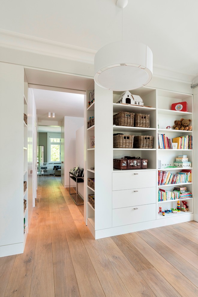 Photo of a traditional gender-neutral kids' playroom for kids 4-10 years old in Hamburg with white walls and light hardwood floors.