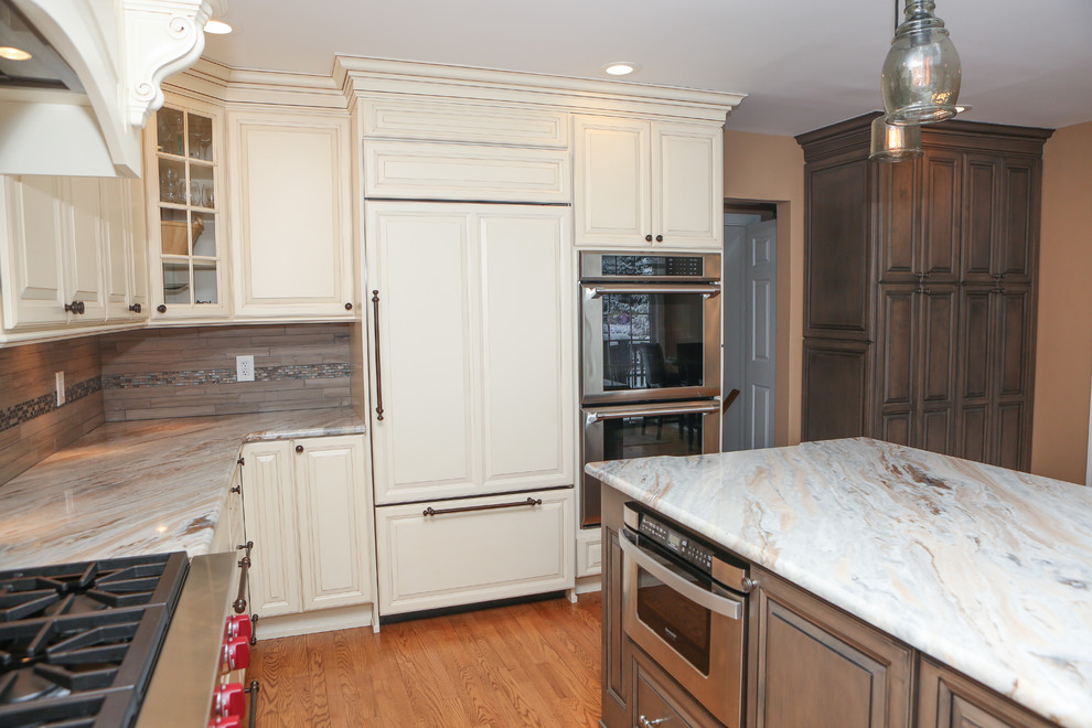 Example of a large transitional u-shaped light wood floor eat-in kitchen design in Newark with an undermount sink, raised-panel cabinets, distressed cabinets, granite countertops, brown backsplash, mosaic tile backsplash, stainless steel appliances and an island