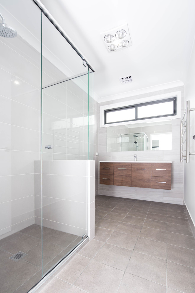 Mid-sized contemporary master bathroom in Canberra - Queanbeyan with furniture-like cabinets, brown cabinets, an alcove shower, a one-piece toilet, gray tile, porcelain tile, grey walls, porcelain floors, an integrated sink, engineered quartz benchtops, grey floor and a hinged shower door.