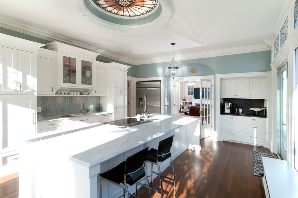 Inspiration for a mid-sized traditional galley open plan kitchen in Vancouver with a double-bowl sink, shaker cabinets, white cabinets, marble benchtops, green splashback, glass tile splashback, stainless steel appliances, medium hardwood floors and with island.