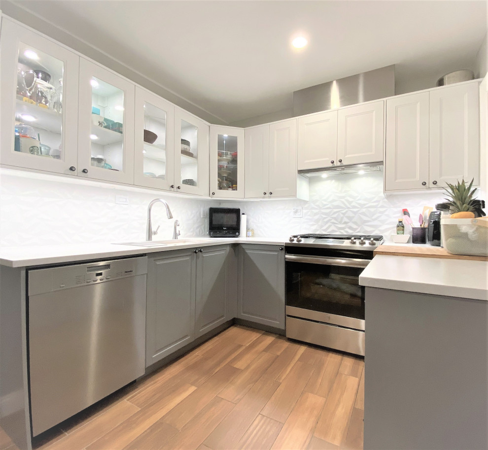 Example of a mid-sized transitional u-shaped ceramic tile and brown floor enclosed kitchen design with an undermount sink, shaker cabinets, gray cabinets, quartzite countertops, white backsplash, porcelain backsplash, stainless steel appliances, no island and gray countertops