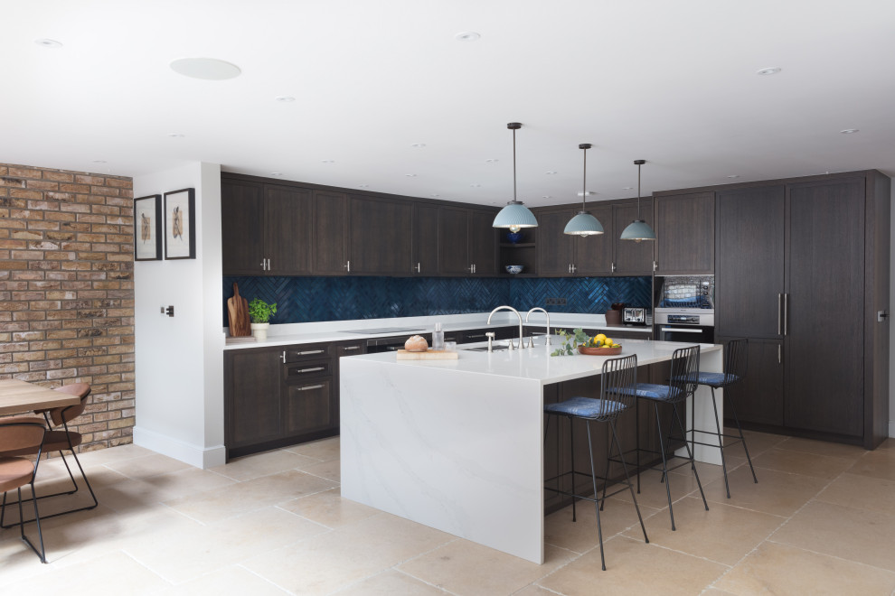 Photo of a large contemporary kitchen/diner in London with a built-in sink, shaker cabinets, dark wood cabinets, quartz worktops, blue splashback, metro tiled splashback, stainless steel appliances, limestone flooring, an island and white worktops.