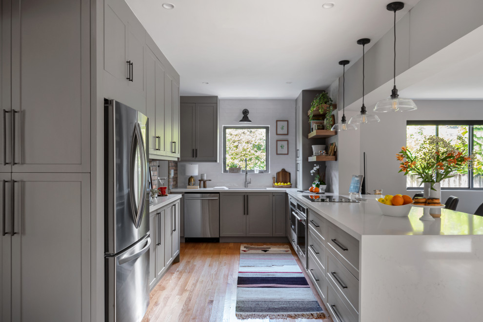 Design ideas for a mid-sized transitional galley eat-in kitchen in Miami with an undermount sink, shaker cabinets, grey cabinets, quartz benchtops, white splashback, subway tile splashback, stainless steel appliances, medium hardwood floors, a peninsula and white benchtop.