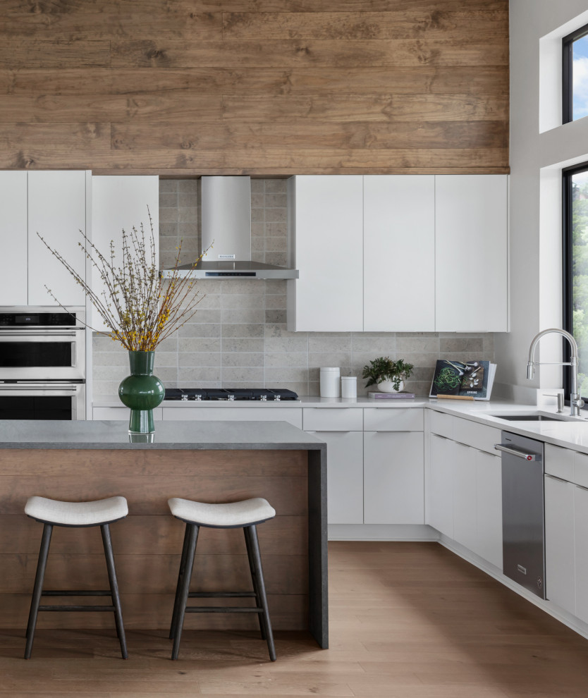 Design ideas for a mid-sized contemporary u-shaped eat-in kitchen in Austin with an undermount sink, flat-panel cabinets, white cabinets, quartz benchtops, grey splashback, porcelain splashback, stainless steel appliances, medium hardwood floors, with island, brown floor and multi-coloured benchtop.