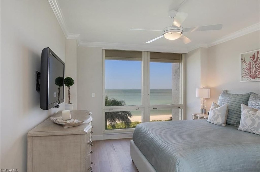Inspiration for a small beach style guest bedroom in Miami with beige walls and light hardwood floors.