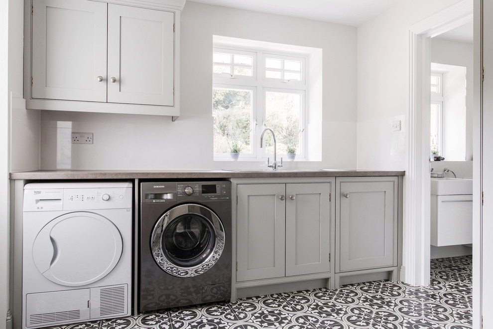 Inspiration for an expansive contemporary u-shaped utility room in Kent with shaker cabinets, grey cabinets, ceramic floors, a side-by-side washer and dryer, a single-bowl sink, laminate benchtops, grey walls, yellow floor and grey benchtop.