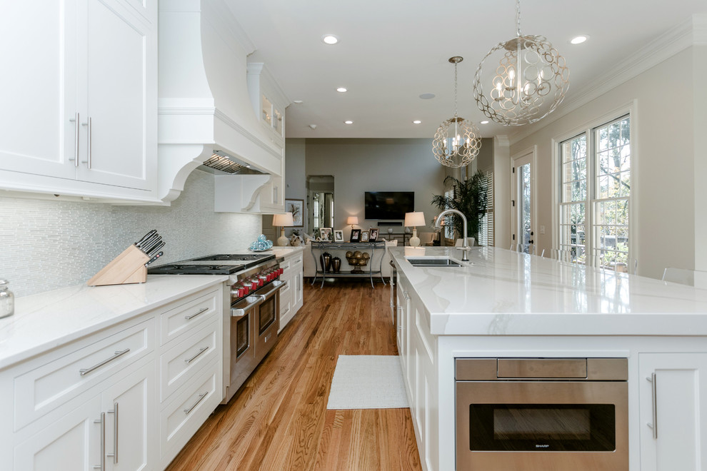 Light wood floor eat-in kitchen photo with a double-bowl sink, beaded inset cabinets, white cabinets, quartz countertops, stainless steel appliances, an island and white countertops