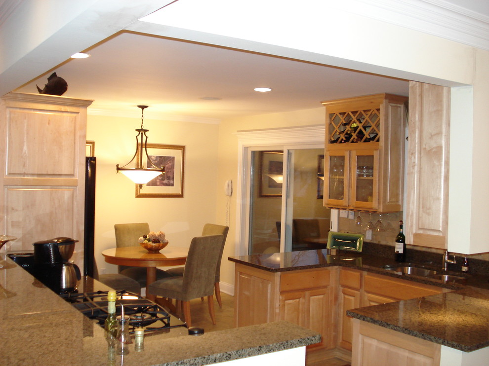 Eat-in kitchen - mid-sized traditional eat-in kitchen idea in Chicago with a double-bowl sink, raised-panel cabinets, light wood cabinets, granite countertops, beige backsplash, black appliances and a peninsula
