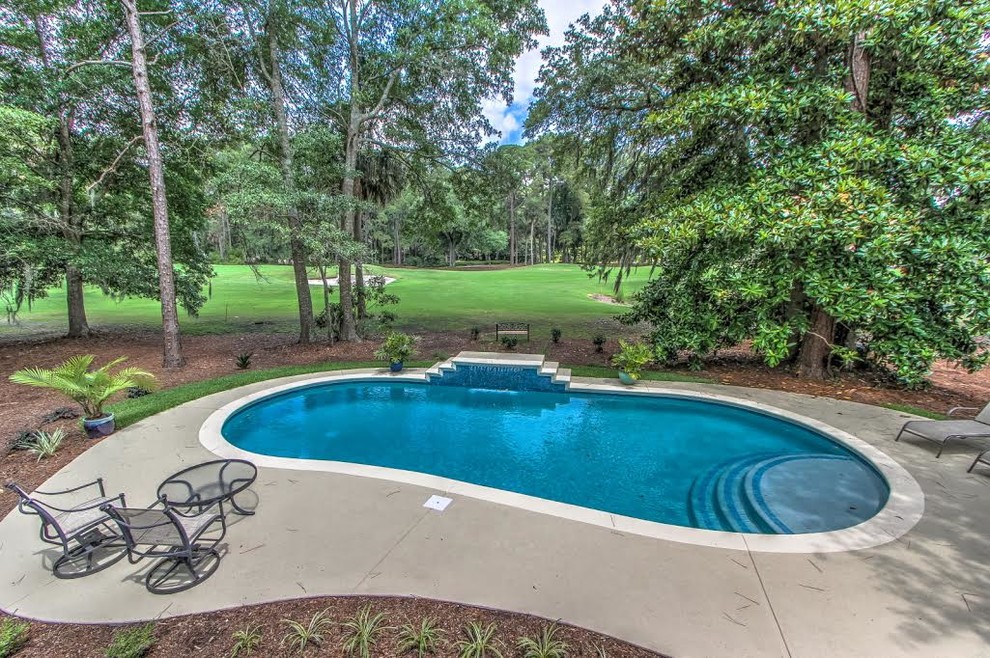 Example of a large backyard stamped concrete and round lap pool fountain design
