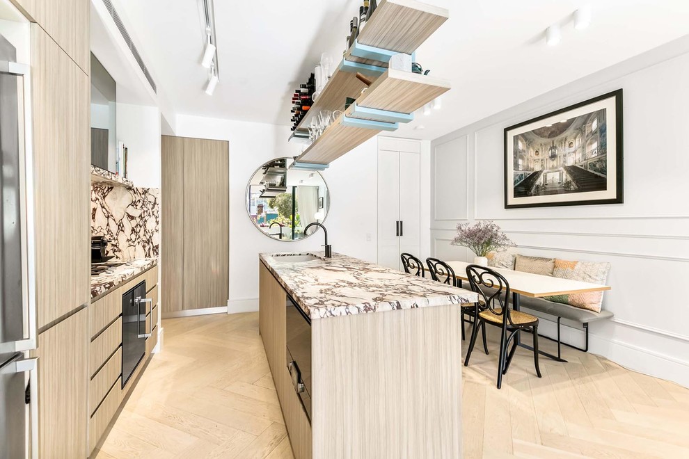 Inspiration for a small contemporary galley open plan kitchen in Sydney with an undermount sink, light wood cabinets, marble benchtops, multi-coloured splashback, marble splashback, black appliances, light hardwood floors, with island, beige floor, flat-panel cabinets and multi-coloured benchtop.