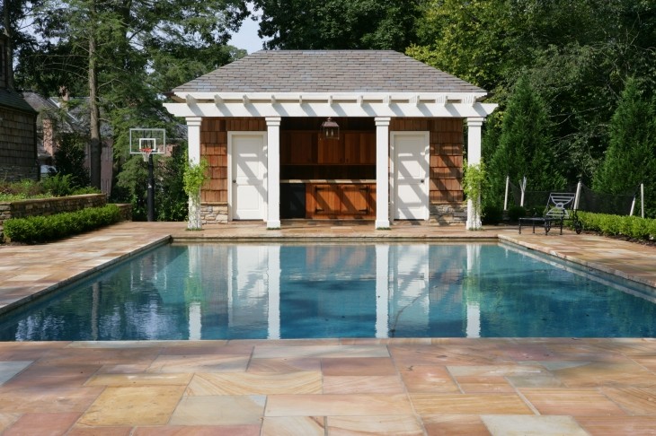 This is an example of a large arts and crafts backyard rectangular lap pool in Other with a pool house and natural stone pavers.
