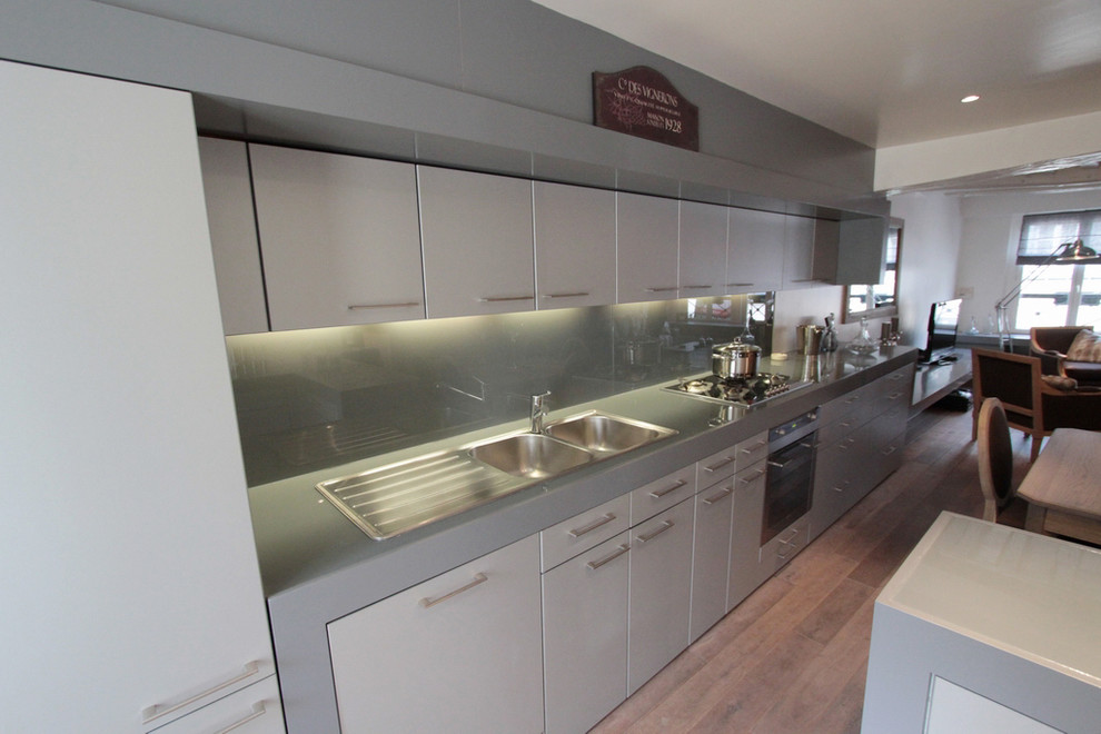 This is an example of a large modern single-wall open plan kitchen in Paris with grey splashback, medium hardwood floors, with island and brown floor.