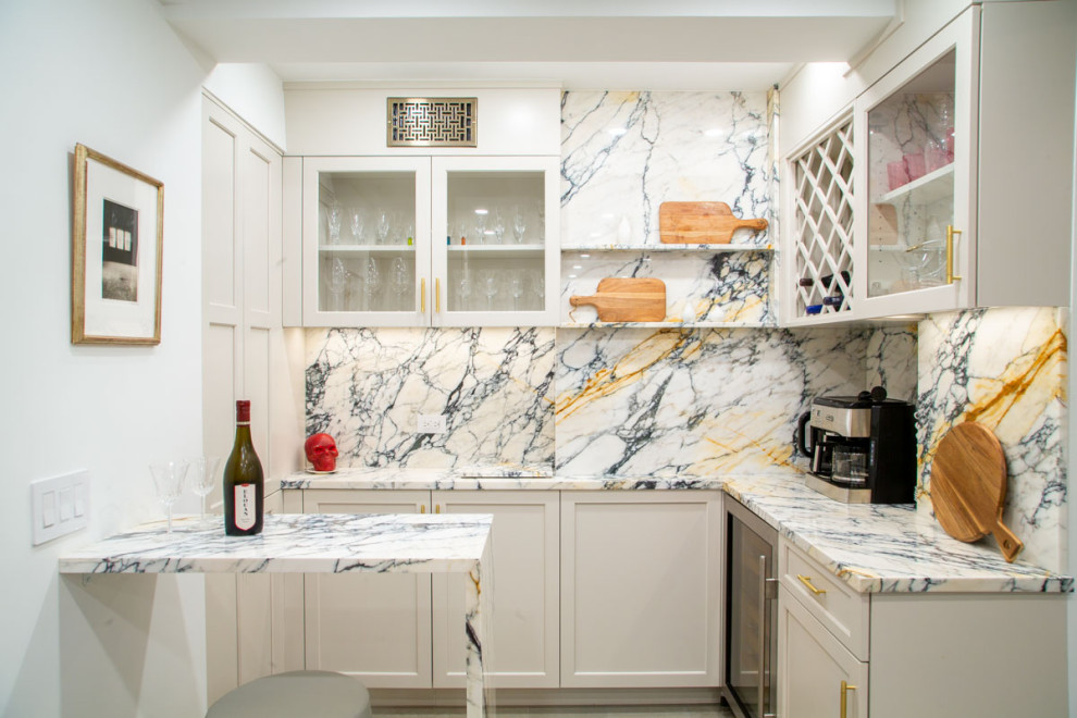 Design ideas for a large transitional u-shaped wet bar in New York with shaker cabinets, beige cabinets, solid surface benchtops and stone slab splashback.
