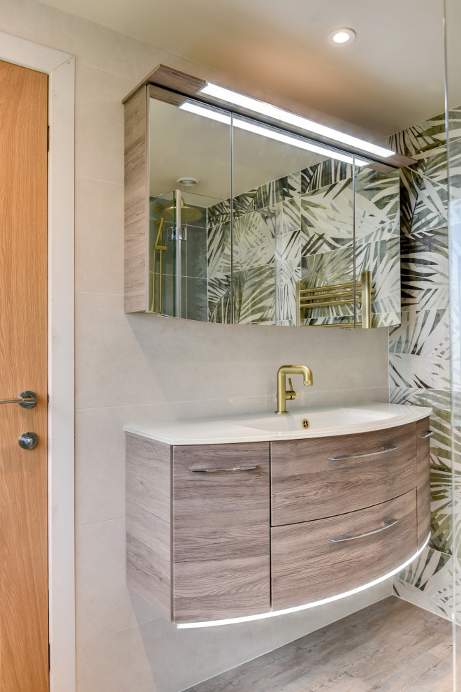 Powder room - mid-sized tropical green tile and ceramic tile medium tone wood floor and brown floor powder room idea in Sussex with flat-panel cabinets, medium tone wood cabinets, a one-piece toilet, multicolored walls, a drop-in sink, white countertops and a floating vanity