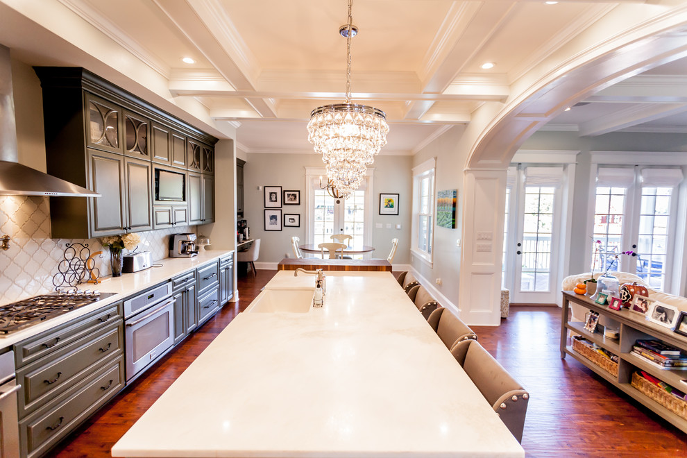 Photo of a large traditional galley eat-in kitchen in Jacksonville with a farmhouse sink, raised-panel cabinets, green cabinets, granite benchtops, white splashback, glass tile splashback, stainless steel appliances, medium hardwood floors and with island.