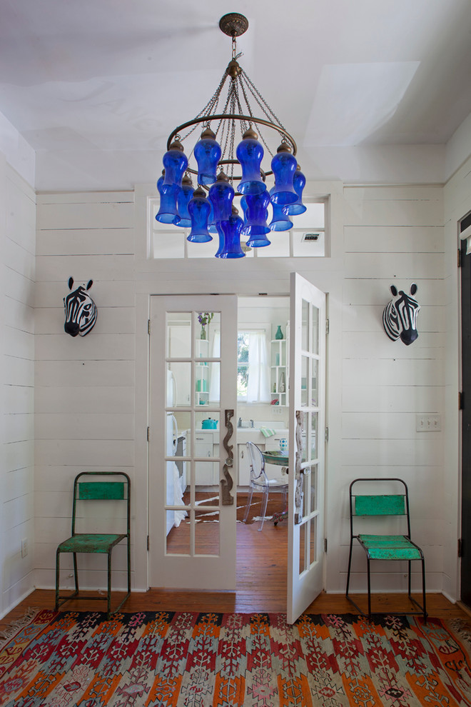 This is an example of an eclectic vestibule in Atlanta with white walls and medium hardwood floors.