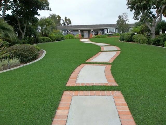 This is an example of a large traditional front yard full sun xeriscape for summer in San Diego with a garden path and natural stone pavers.