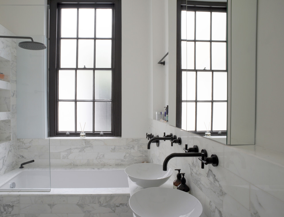 Photo of a contemporary bathroom in London with a drop-in tub, a shower/bathtub combo and marble floors.