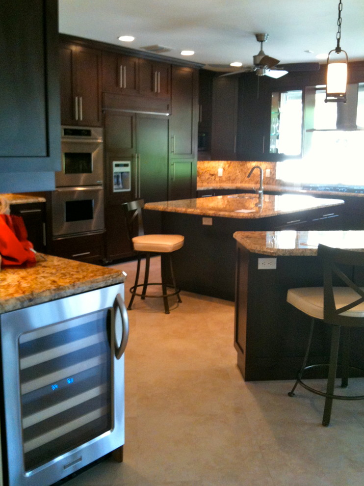 Large transitional u-shaped travertine floor and beige floor open concept kitchen photo in Miami with an undermount sink, shaker cabinets, dark wood cabinets, granite countertops, multicolored backsplash, stone tile backsplash, stainless steel appliances and an island