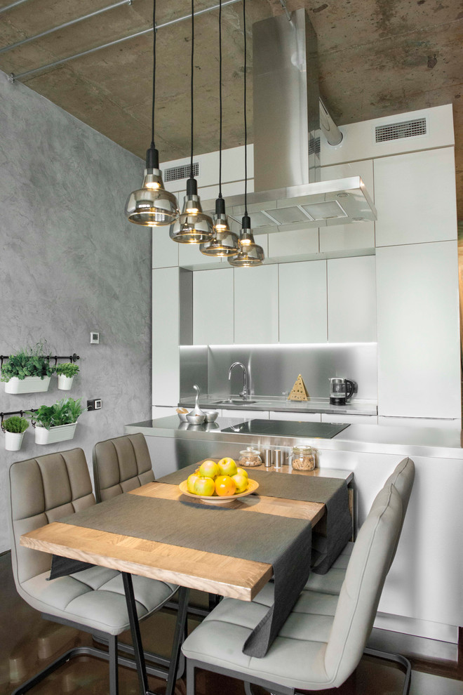 Inspiration for a mid-sized industrial galley kitchen in Moscow with flat-panel cabinets, white cabinets, stainless steel benchtops, metallic splashback, metal splashback, panelled appliances, concrete floors, with island and brown floor.