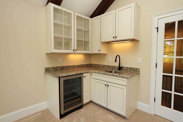 Photo of a traditional l-shaped wet bar in Charlotte with an undermount sink, recessed-panel cabinets, white cabinets, granite benchtops and carpet.