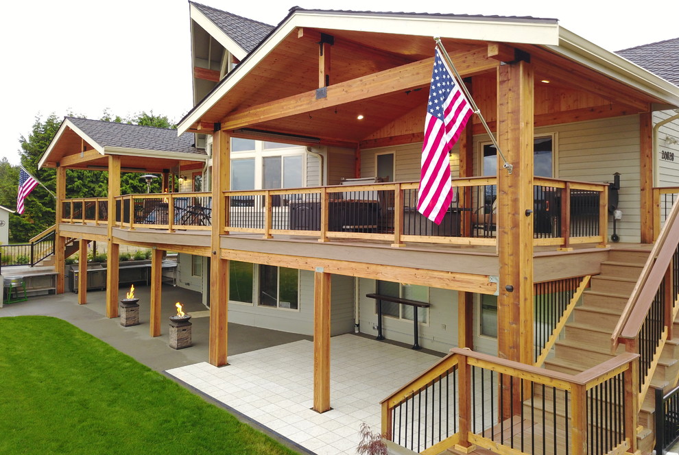 Large country backyard deck in Seattle with a roof extension and an outdoor kitchen.