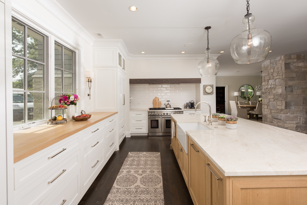 Example of a large classic dark wood floor and brown floor kitchen design in Chicago with white cabinets, paneled appliances, an island and shaker cabinets
