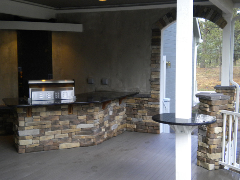 Backyard outdoor kitchen deck photo in Denver with a roof extension