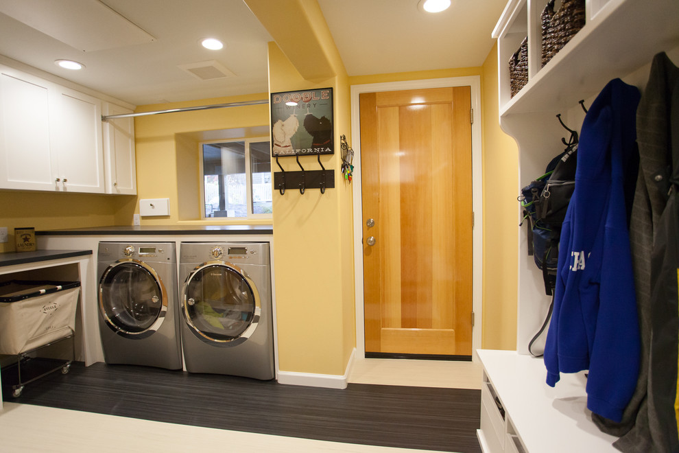 This is an example of a large transitional l-shaped utility room in Seattle with shaker cabinets, white cabinets, laminate benchtops, yellow walls, linoleum floors and a side-by-side washer and dryer.