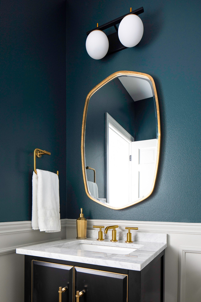 Inspiration for a small modern cloakroom in Milwaukee with raised-panel cabinets, black cabinets, a one-piece toilet, blue walls, a submerged sink, marble worktops, white worktops, a built in vanity unit and wainscoting.