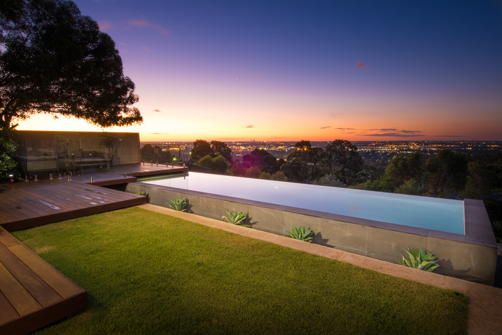 This is an example of a large backyard rectangular infinity pool in Perth with a water feature and decking.