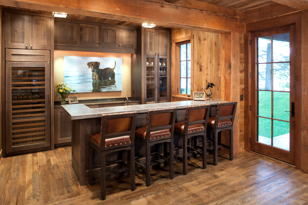 Country l-shaped seated home bar in Minneapolis with distressed cabinets and medium hardwood floors.