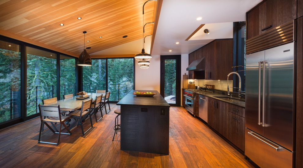 Inspiration for a country eat-in kitchen in San Francisco with an undermount sink, flat-panel cabinets, dark wood cabinets, soapstone benchtops, green splashback, ceramic splashback, stainless steel appliances, medium hardwood floors and with island.