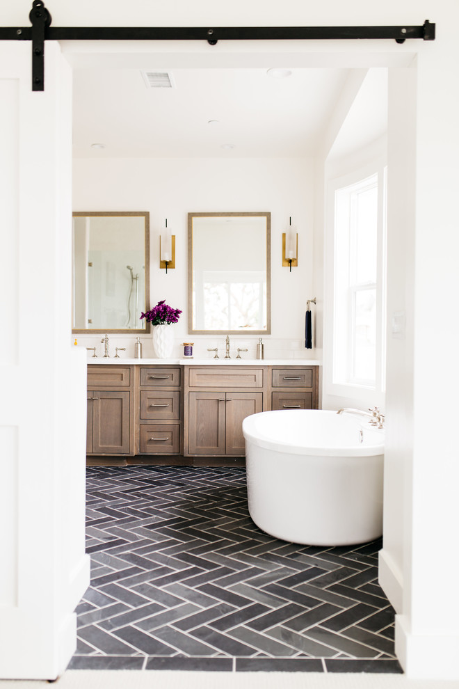 Photo of a large country master bathroom in San Diego with shaker cabinets, dark wood cabinets, a freestanding tub, white walls, porcelain floors, an undermount sink, engineered quartz benchtops and black floor.
