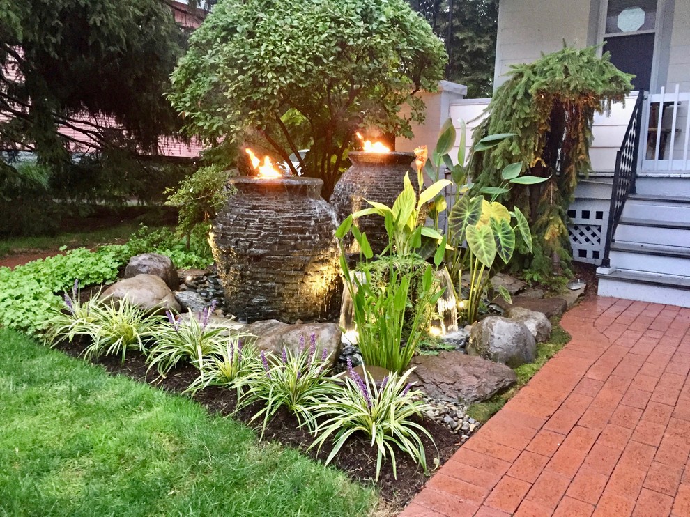 This is an example of a small traditional front yard partial sun formal garden for summer in New York with a fire feature and brick pavers.