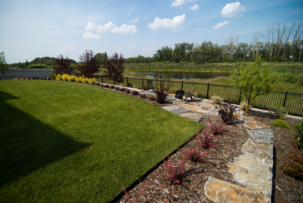 This is an example of a large traditional partial sun backyard mulch formal garden in Calgary for spring.