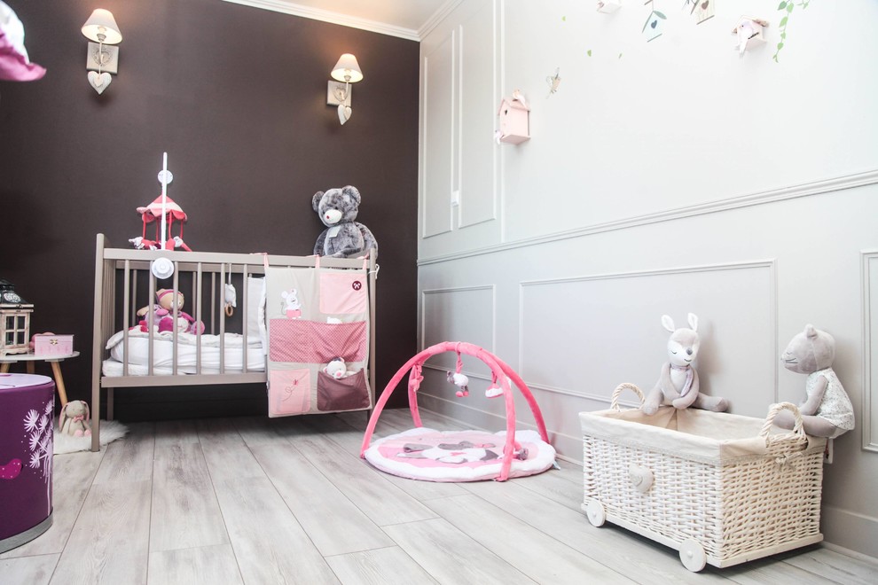 Photo of a mid-sized traditional nursery for girls with beige walls, laminate floors and beige floor.