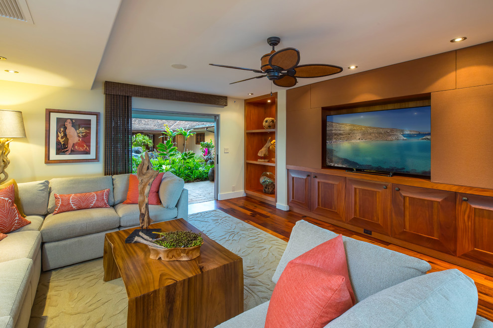 Inspiration for a tropical family room in Hawaii with yellow walls, medium hardwood floors, a wall-mounted tv and orange floor.
