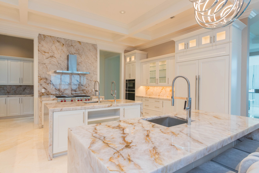 Example of a huge transitional u-shaped marble floor and white floor open concept kitchen design with an undermount sink, flat-panel cabinets, white cabinets, quartzite countertops, white backsplash, stone slab backsplash and two islands