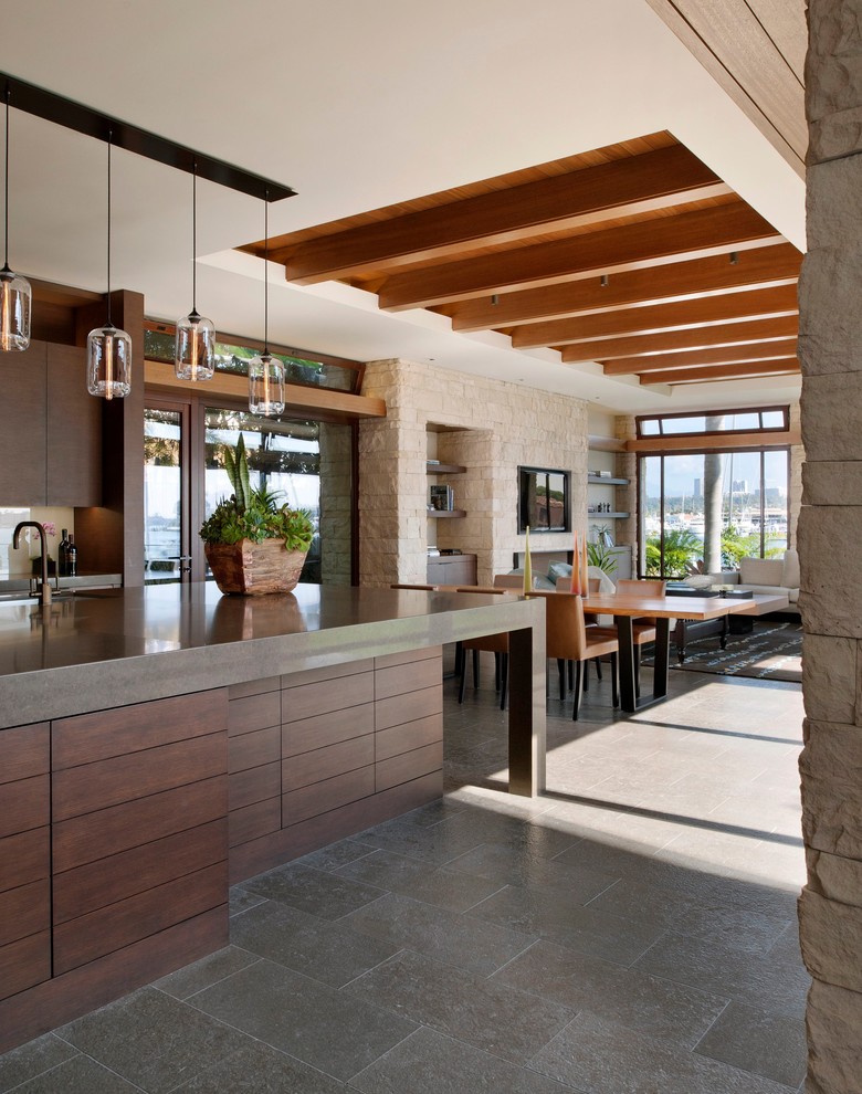 This is an example of a contemporary open plan kitchen in Orange County with flat-panel cabinets and dark wood cabinets.